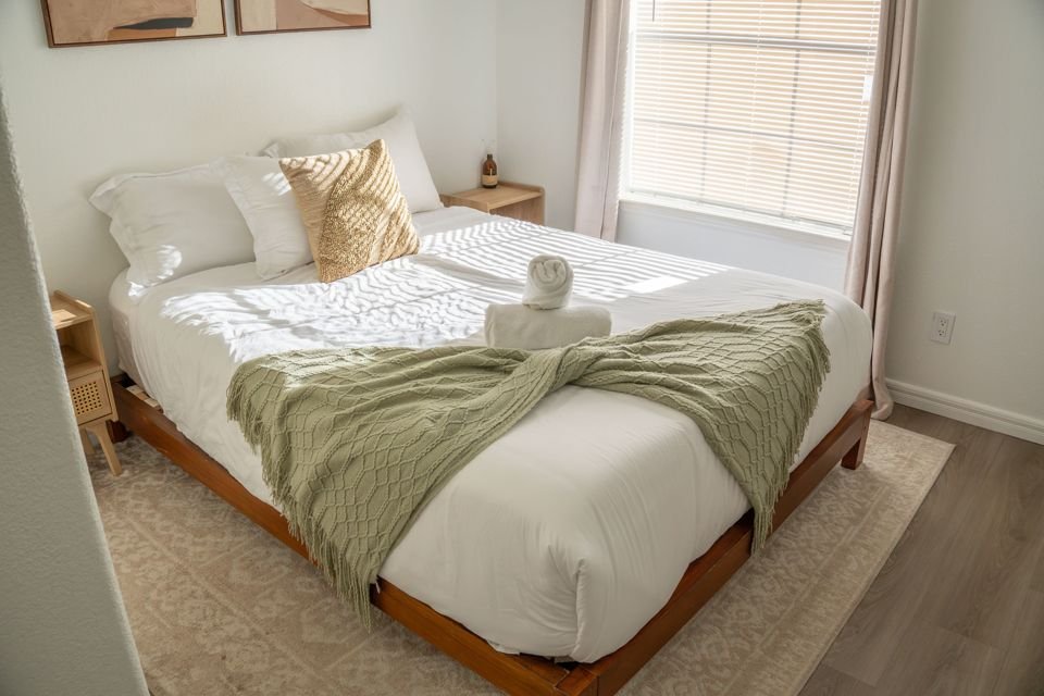 Bedroom with queen bed and green throw