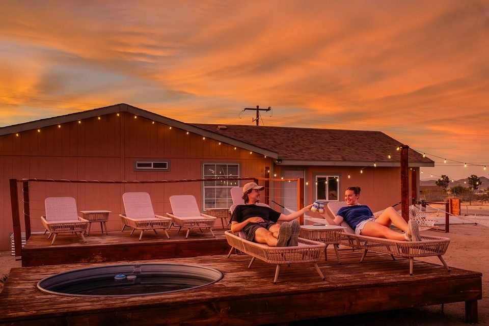Guests relaxing on the loungers by the cowboy pool at sunset